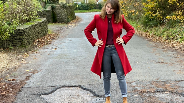 Lisa Spivey stood next to large potholes
